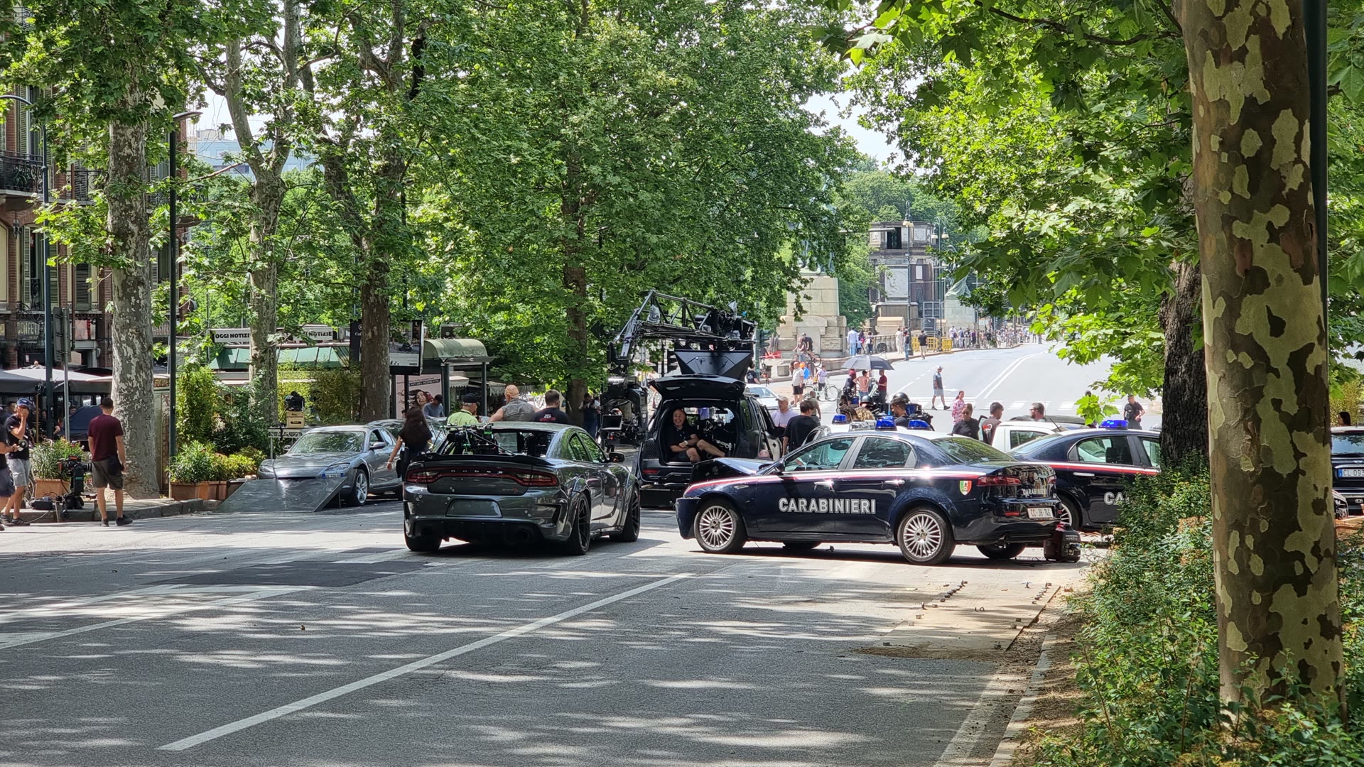 Wide Fast X street setup in Rome with a camera vehicle, crew, an action car and Carabinieri vehicles.